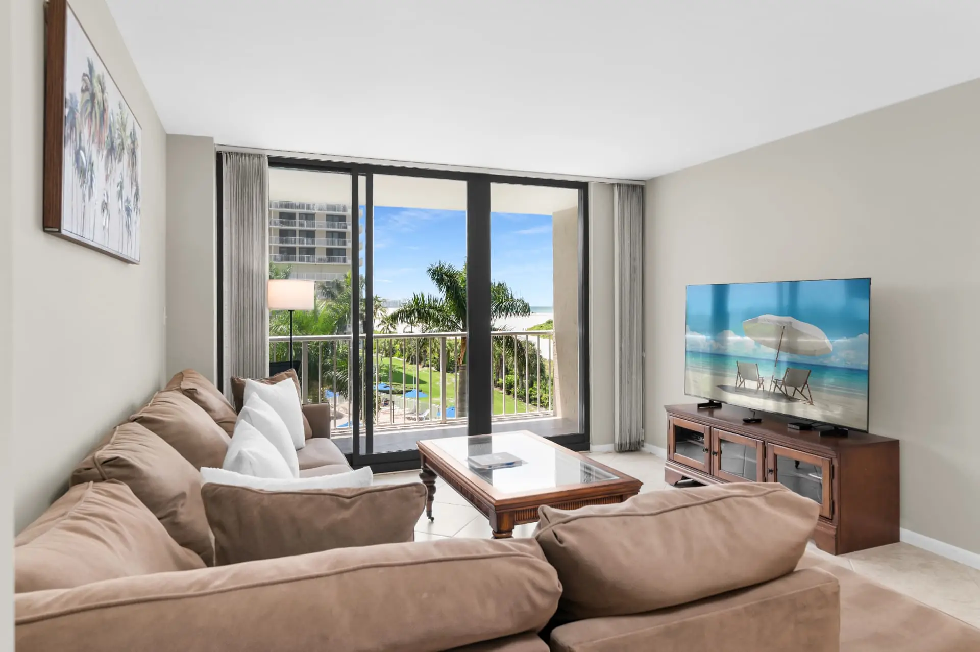Living room at Seaview 409 with a sectional sofa, wall-mounted television and sliding glass doors opening to the balcony