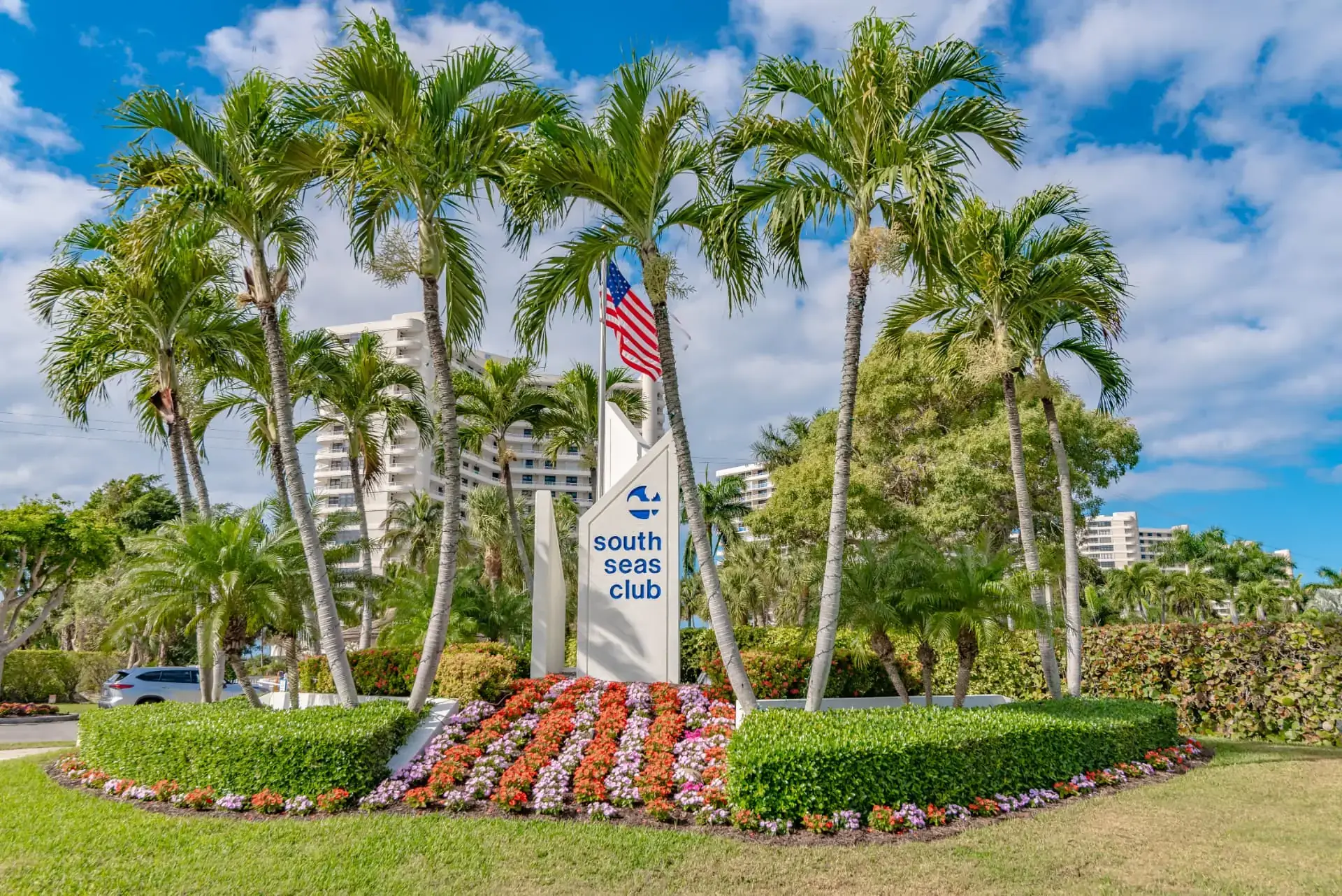 South Seas Club entrance sign framed by palm trees and flowering landscaping